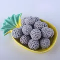 Close-up of gray crocheted cotton yarn balls on a decorative yellow pineapple ceramic tray - Gray