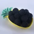 Macro shot of 20mm black hand-knit crochet yarn beads displayed in a yellow pineapple dish - Black