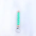 Detail of mint green silicone and wood bead baby pacifier clip with secure plastic fastener - Christmas Green