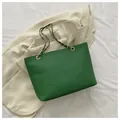 Green faux crocodile tote bag with gold chain strap shown on neutral background - Green