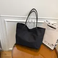 Bolso tote minimalista de lona negra con asas finas de cuero sobre una mesa elegante - Estilo Lona Todo Negro / Negro