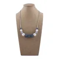 Silicone teething necklace for babies with grey and purple beads on jute display - White