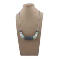 Silicone teething necklace with sage green and gray geometric beads on a jewelry display - Light Green