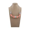 Silicone and wood teething necklace in grey and coral orange on a linen display - Rose Pink