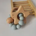 Close-up of baby teether with beech wood star, ring and blue silicone beads on a stand - Grey Blue