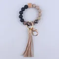 Macro detail of silicone beads, wooden geometric bead, and snakeskin tassel keychain charm - Khaki