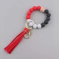 Detail of red and black beaded keychain bracelet with faux leather tassel and gold ring - Red