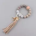 Detail van siliconen kralenarmband met geometrische houten kraal en lange lederen kwast - Khaki