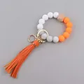 Detail van siliconen kralenarmband met feloranje kwastje en gouden metalen ring sluiting - Oranje