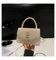 Dettaglio borsa chic in pelle crema con paillettes scintillanti e logo SS dorato in stile design - Oro