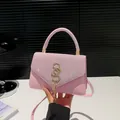 Sac à bandoulière rose pailleté avec logo SS doré et pompon sur un bureau blanc - Rose