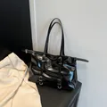 Glossy black tote bag with silver buckles and shoulder straps for daily commuting - Black