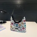 Floral woven canvas hobo bag with black shoulder strap and fashion label on table - Black