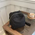 Minimalistischer schwarzer Segeltuch-Rucksack mit orangem Etikett und silbernem Reißverschluss - Schwarz