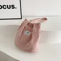 Detaillierte Makroansicht der rosa Cord-Einkaufstasche mit Streifentextur und Goldknopf - Rosa