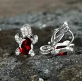 Macro shot of silver turtle earrings with red oval gemstone and white zircon detailing - Garnet Red
