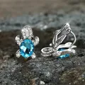 Detail view of silver turtle ear clip with a large blue zircon on a dark stone - Aqua