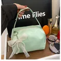 Light green handbag with pearl lace bow charm shown held by a fashion model - With Pendant Decoration / Green