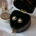 Macro view of vintage clover earrings with white opal set in a heart shaped gift box - Gold