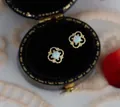 Macro detail of gold four-leaf clover opal stud earring in black velvet jewelry box - Silver