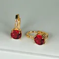 Dettaglio di orecchini a cerchio dorati con grande zircone rosso tondo a quattro griffe - Oro Rosso Zirconia
