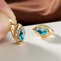 Vue macro des boucles d'oreilles en or avec pierre marquise bleue et détails ciselés - Bleu clair