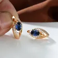 Dettaglio macro di orecchini in oro champagne con pietra blu ovale e cristalli incastonati - Blu