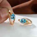 Dettaglio di orecchini a cerchio in oro rosa con gemma blu ovale e piccoli zirconi - Acqua