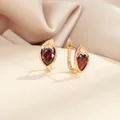 Gros plan de boucles d'oreilles goutte or champagne avec zircon rouge sur soie - Rouge