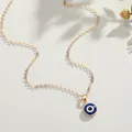 Turkish Evil Eye pendant necklace with a golden chain on a minimal textured background - Dark Blue