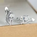 Macro-opname van zilveren huggie oorbellen met peervormige zirkonia en pavé details - Platinawit