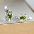 Detailopname van zilveren oorringen met druppelvormige groene zirkonia stenen erin - Platina Olijfgroen