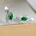 Macro-opname van zilveren oorringen met peergeslepen smaragdgroene stenen en witte zirkonia's - Platina Verguld Groen
