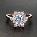 Roségouden bloemring met centrale steen en kristallen op getextureerde achtergrond - US 6 / Roségoud/Witte Zirkonia