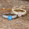 Golden oval white opal ring with pavé diamond band on a textured stone surface - US 7 / Gold Blue Opal