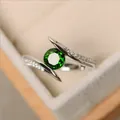 Macro shot of silver ring featuring a large round green gemstone with pavé zircon accents - US 5 / Green Zirconia