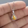 Elegant pear-cut yellow gemstone pendant necklace with halo diamond setting on hand - White Gold With Yellow Zircon