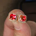 Detailed macro of gold square studs with a red cushion-cut gem and zircon halo - Gold-Tone Pink Yellow