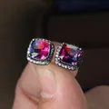 Macro detail of square halo earrings with multi-color gradient stones held by fingers - Black Gold Plated Rose Blue Zircon