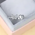 Gros plan d'une bague papillon et cœur avec gravure lettre H sur un écrin - Ouvert Réglable / Platine Lettre H