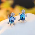 Macro detail of turtle stud earrings featuring dark blue crystals and cubic zirconia - White Gold Plated Blue Green Zircon