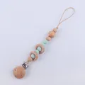Close-up of a baby pacifier clip with green silicone beads and natural beech wood rings - Light Green