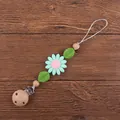 Detail of wooden pacifier clip with silicone sunflower and beads on dark wood background - Green
