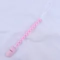 Detailed view of pink beaded pacifier clip with secure plastic clasp on white fabric - Pink