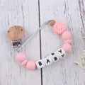 Close-up of pink daisy silicone pacifier clip with wooden beads and baby letters - Pink