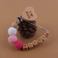 Détail de l'attache-tétine en bois avec boules au crochet et gravure I Love Mom - Cœur