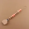 Detail of wooden heart pacifier clip with silicone beads on a brown background - Rose Pink