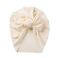 Detailed view of the ribbed knit fabric and large decorative bow on the cream baby turban hat - Beige