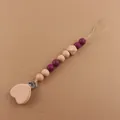 Detailed view of handmade baby pacifier clip with purple silicone and heart beechwood beads - Burgundy