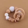 Détail d'un hochet bébé en bois et silicone avec perles gravées du mot BABY - Blanc
